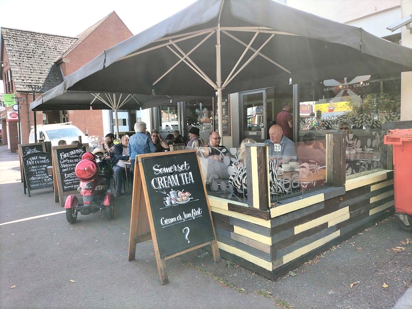 The terrace outside Cream under big umbrellas, with the Somerset Cream Tea chalkboard on the pavement